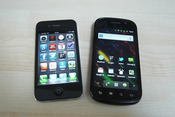 An iPhone 4 and a Google Nexus S on a beech coloured desk.