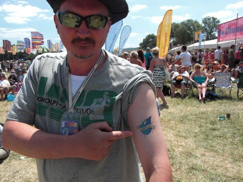 Barry at the Glastonbury Festival. He is pointing to a WaterAid temporary tattoo that he has on his left arm.
